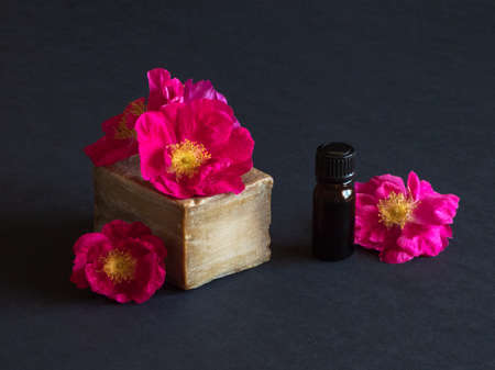 Handmade soap and roses flowers on a black table.の写真素材