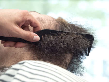 Trimming the mustache in a barbershop. Details of trimming. Cropped closeup of a barber trimming beard.の写真素材