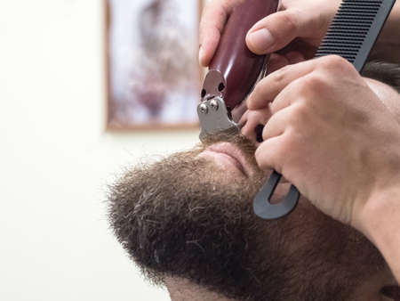 Trimming the mustache in a barbershop. Details of trimming. Cropped closeup of a barber trimming beard.の写真素材