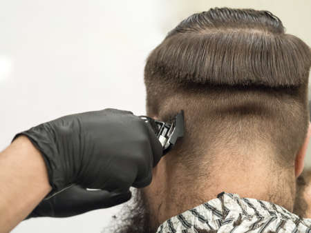 Trimming the mustache in a barbershop. Details of trimming. Cropped closeup of a barber trimming...