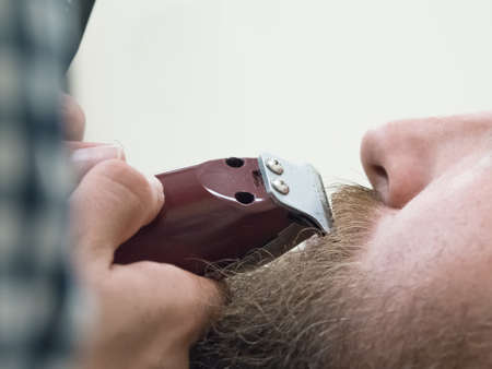 Trimming the mustache in a barbershop. Details of trimming. Cropped closeup of a barber trimming beard.の写真素材