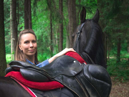 Beautiful girl smile at her horse. Outdoors portrait in green park.の写真素材