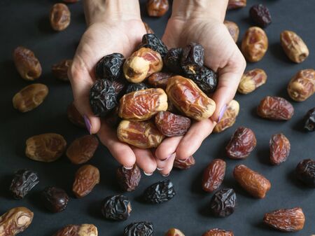 Dates fruit in the palms on a black background.