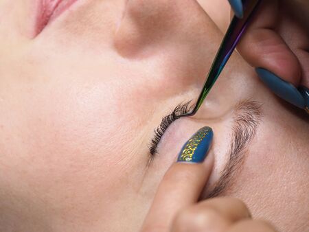 The procedure of lamination of the eyelashes. Eyelashes with tweezers.
