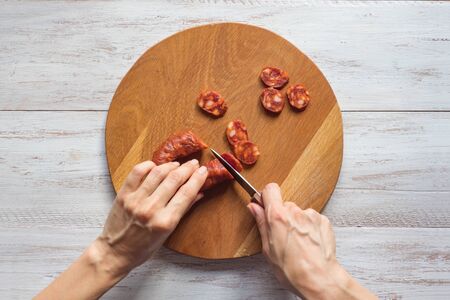 Chorizo sausage slices on a white wooden background. Top view.