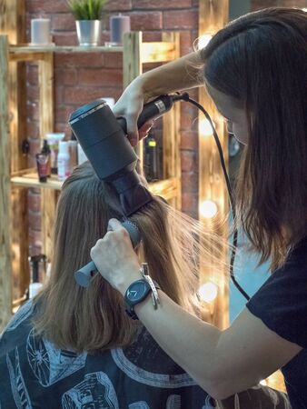 Drying long women hair with a hairdryer in a beauty salon.の写真素材
