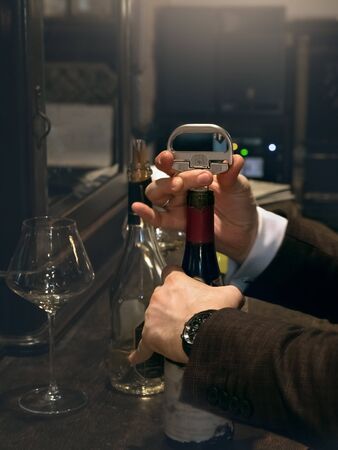 The sommelier opens a bottle of red vintage wine. Close up.の写真素材