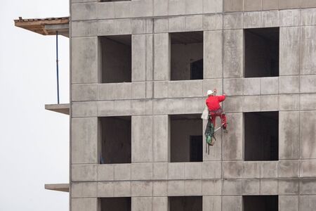 Working high-rise worker working on the facade of the building under construction.