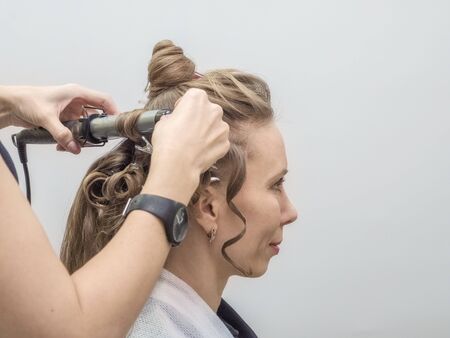Hair styling process. Creating an evening hairstyle. Fashionable stylish female hairstyle