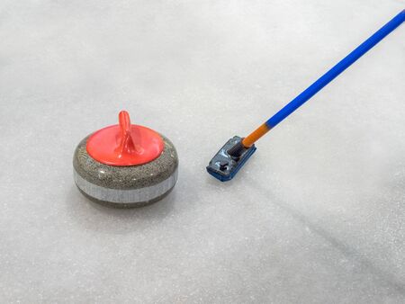 Broom and stone for curling on ice of a indoors rinkの写真素材