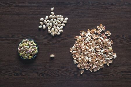Pistachios are scattered on the brown table. Peeling nuts from the shell. The manual labor concept.の写真素材