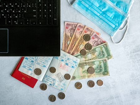A medical mask, passport with visas and Arabic dirhams. Pandemic and the economic crisis of the...