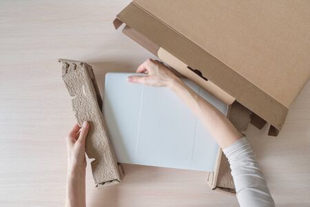 Unpacking a new laptop from a cardboard box. Hands open the box. Unpacking the received parcel. Top view.の写真素材