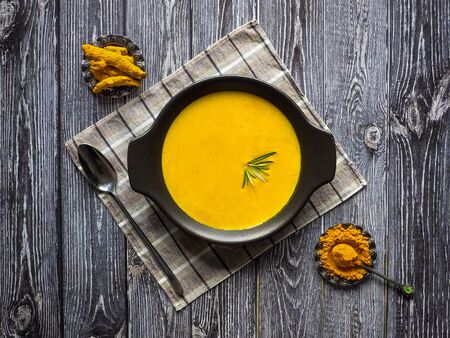 Healthy curcuma cream soup on black wooden background. Prevention of antiviral infections. Spices for ayurvedic treatment. Alternative medicine concept.の写真素材