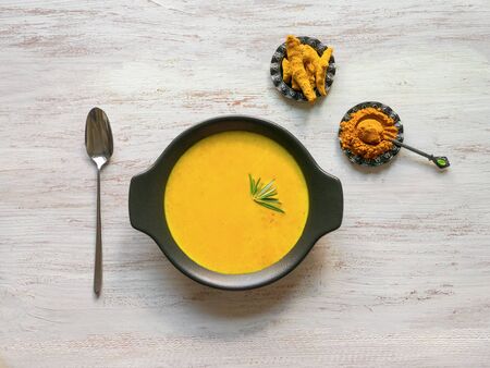 Healthy curcuma cream soup on white wooden background. Prevention of antiviral infections. Spices for ayurvedic treatment. Alternative medicine concept.の写真素材