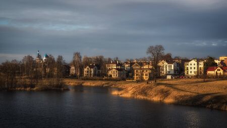 Panoramic bright spring landscape with houses near a lake in the evening. Eco-friendly cottage village on the shore of the lake.の写真素材
