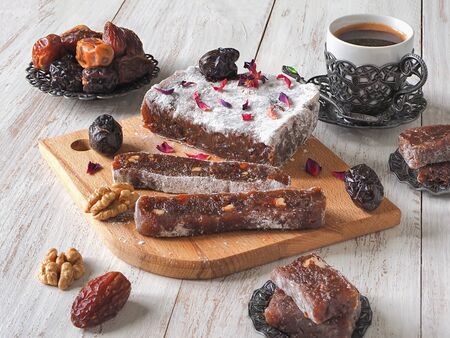 Homemade marmalade sweets with date fruits and nuts, eastern candies on a white wooden surface.