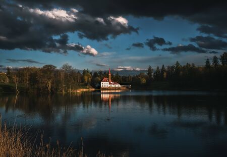 Beautiful dramatic landscape with a castle by the lake and dark storm clouds.の写真素材