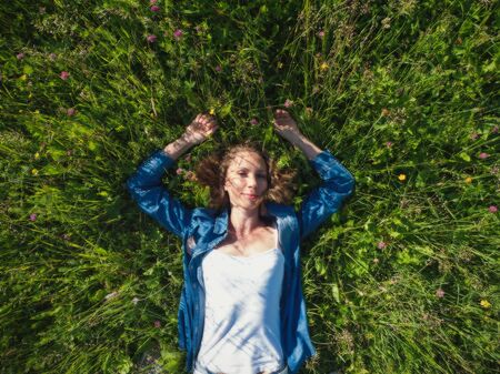 Beautiful woman lying on a green flower field.