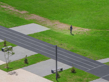 Lawn mower, municipal services work on a green field in the courtyard. New building courtyard.の写真素材
