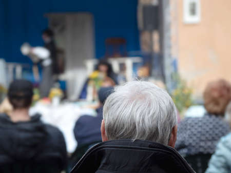 An active pensioner listens to Opera. Back view of the man with a gray hair head in a open air.の写真素材
