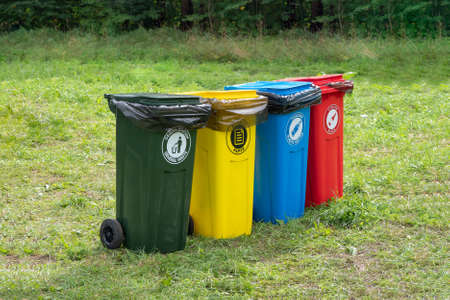 Colored containers for separate garbage collection in green lawn. Translation of labels: General...