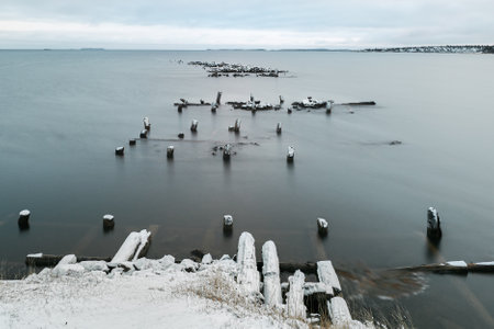 Minimalistic winter Arctic landscape with a net on the shore covered with sparse vegetation and a...