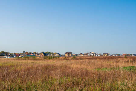 Dacha village on the horizon across the autumn field. Panoramic view.の写真素材