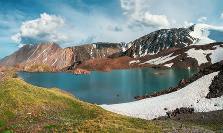 Snowy high-altitude plateau. Panoramic alpine landscape with snow-capped mountain peak under dramatic blue sky. Colorful sunny mountain scenery with snow mountain top. Altai mountainsの写真素材