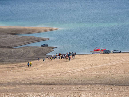 A group of tourists goes to get into the boats. Remote view. Sulak reservoir, Dagestan.の写真素材