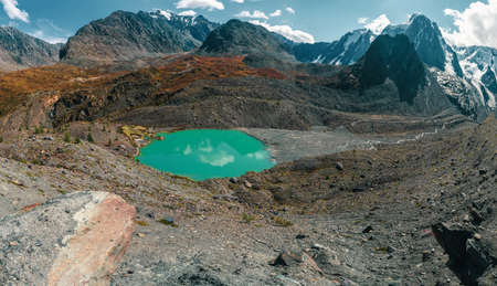 Impressive mountain landscape with a huge snowy mountain and a glacier illuminated by the sun among high rocks. Stunning alpine scenery with a large glacier on top of the mountain.の写真素材