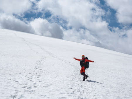 Cheerful tourist is fooling around on a glacier.Tourist hiking up the glacier. Winter hiking in the snow-capped mountains. Extreme recreation and mountain tourism.の写真素材