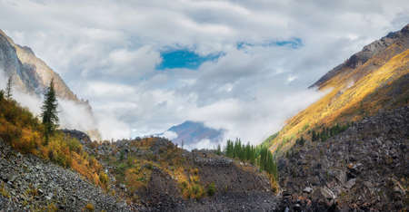 Panoramic view of the autumn mountain, fog over the mountain slopes in the distance, white clouds...