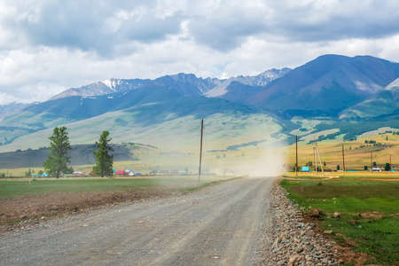 Soft focus. Dust storm over the road in the countryside against the background of mountains.の写真素材