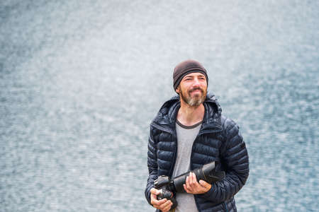 Portrait of a happy travel photographer with a large camera on his hands. Travel freelancer blogger...