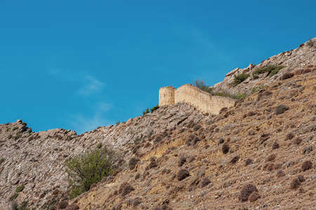 The wall of the old fortress on the hill against the blue sky. Gunib fortress is a historical monument of Dagestan.の写真素材
