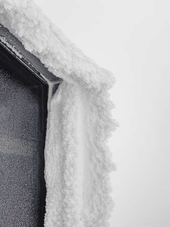 Winter ice window. Icy window to winter in snow. Icy visor over the window. vertical view.の写真素材