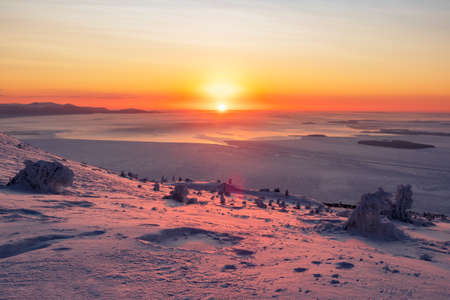 Amazing cold pink dawn over a snowy winter hill. View of the snow-covered tundra and hills. Arctic harsh nature. Mystical fairy tale of the winter frost forest.の写真素材