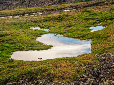 Bright sunny atmospheric scenery on top of spotted snow mountain ridge under dark clouds. Beautiful...