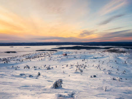 Beautiful Arctic sunset. Scenic colorful sky at dawn. Snow-covered slope of the polar hill in the winter early in the morning. winter polaris landscape. Cold winter weather.の写真素材