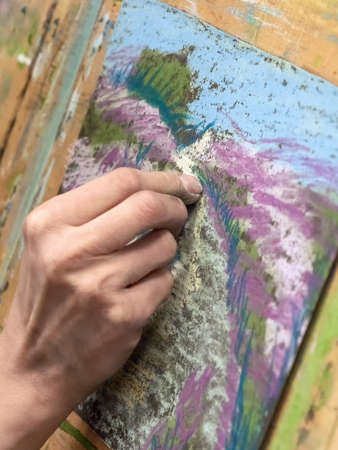 Drawing with pastels close-up. Woman drawing beautiful crocus flowers with soft pastel at table....