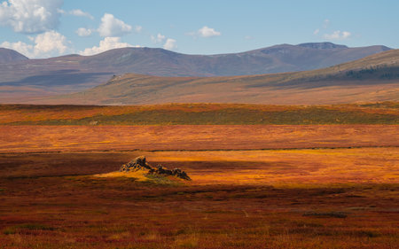 Picturesque autumn mountain plateau with a dramatic view and rays of the sun on the hillside. Dramatic golden light and shadow on the rock in autumn. panoramic view.の写真素材