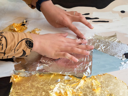 selective focus. Female hands apply gold and silver potal to the picture, distributing it with a...