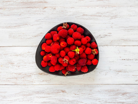 Ripe red berries of Tibetan raspberry on a bowl. copyspace.
