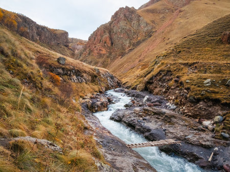Wooden makeshift bridge over a mountain river. Beautiful autumn mountain landscape with bent mountain river.の写真素材