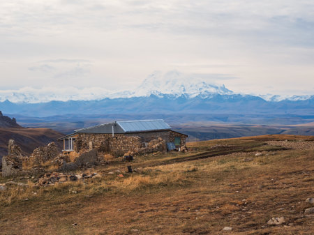 An old stone guest house high in the mountains against the backdrop of snowy majestic peaks....
