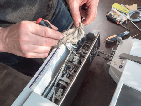 Male master repairs the sewing machine. Internal cleaning of the mechanism. Professional adjustment...