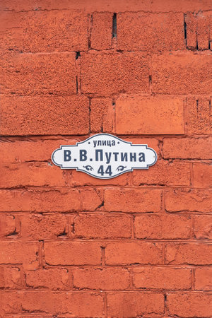 Red brick wall. Street sign VV Putin street located in Armkhi, Ingush Republic, Russiaの写真素材