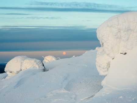 Red full cold moon over a snow-covered slope. winter polar landscape. Cold winter weather. Harsh northern climate. minimalist view.の写真素材