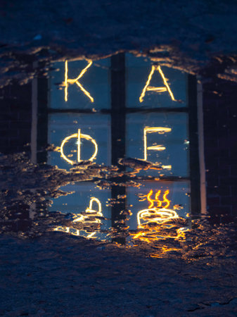 Bright fluorescent sign in Russian "Cafe" is reflected in a puddle on a wet night bridge. coffee shop signboard.の写真素材